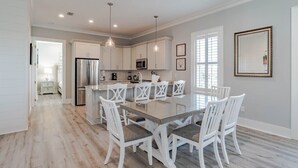 A modern kitchen with white cabinetry, a central island, and pendant lighting.