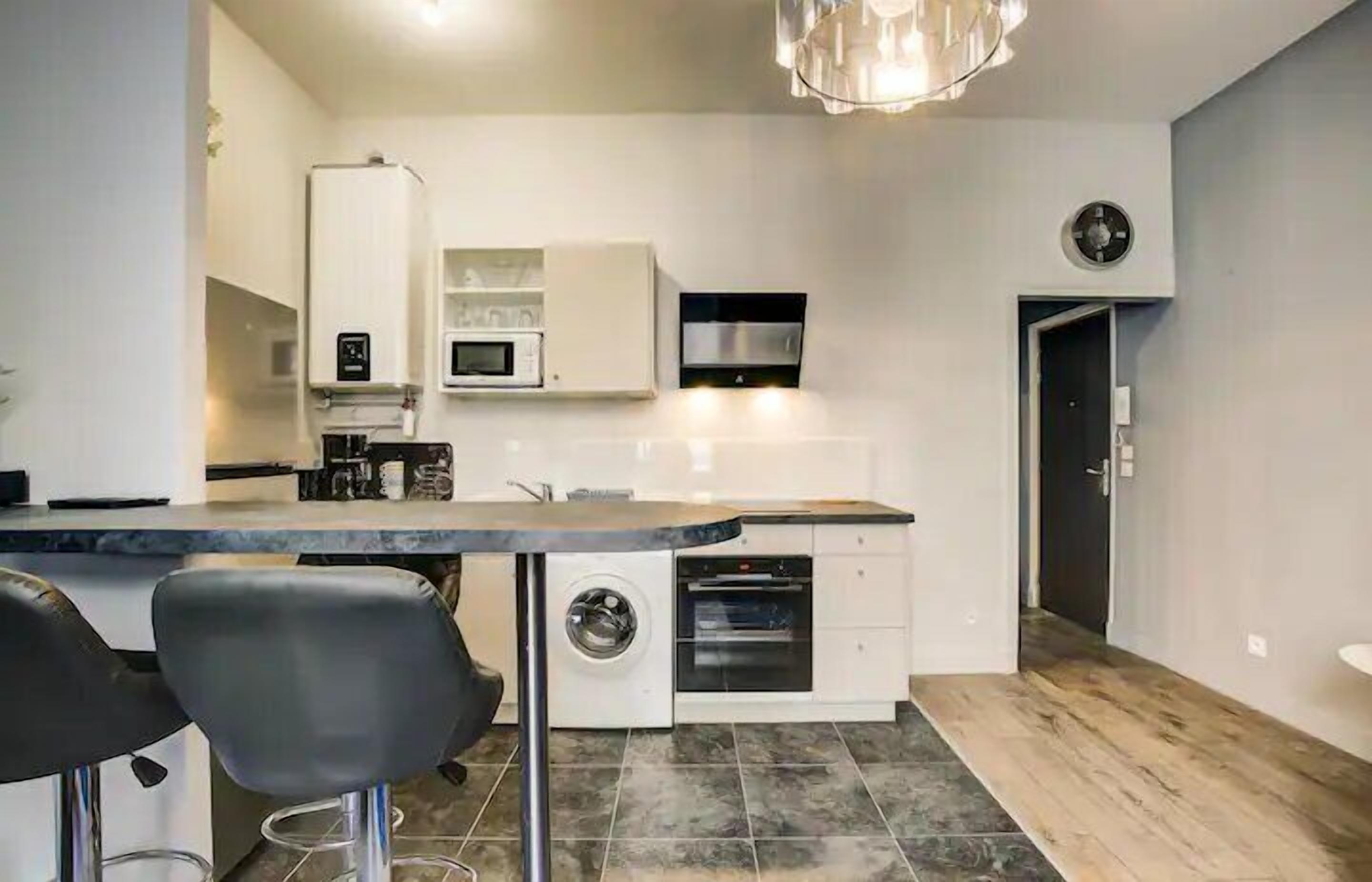 A modern kitchen with a built-in washing machine, microwave, and oven.