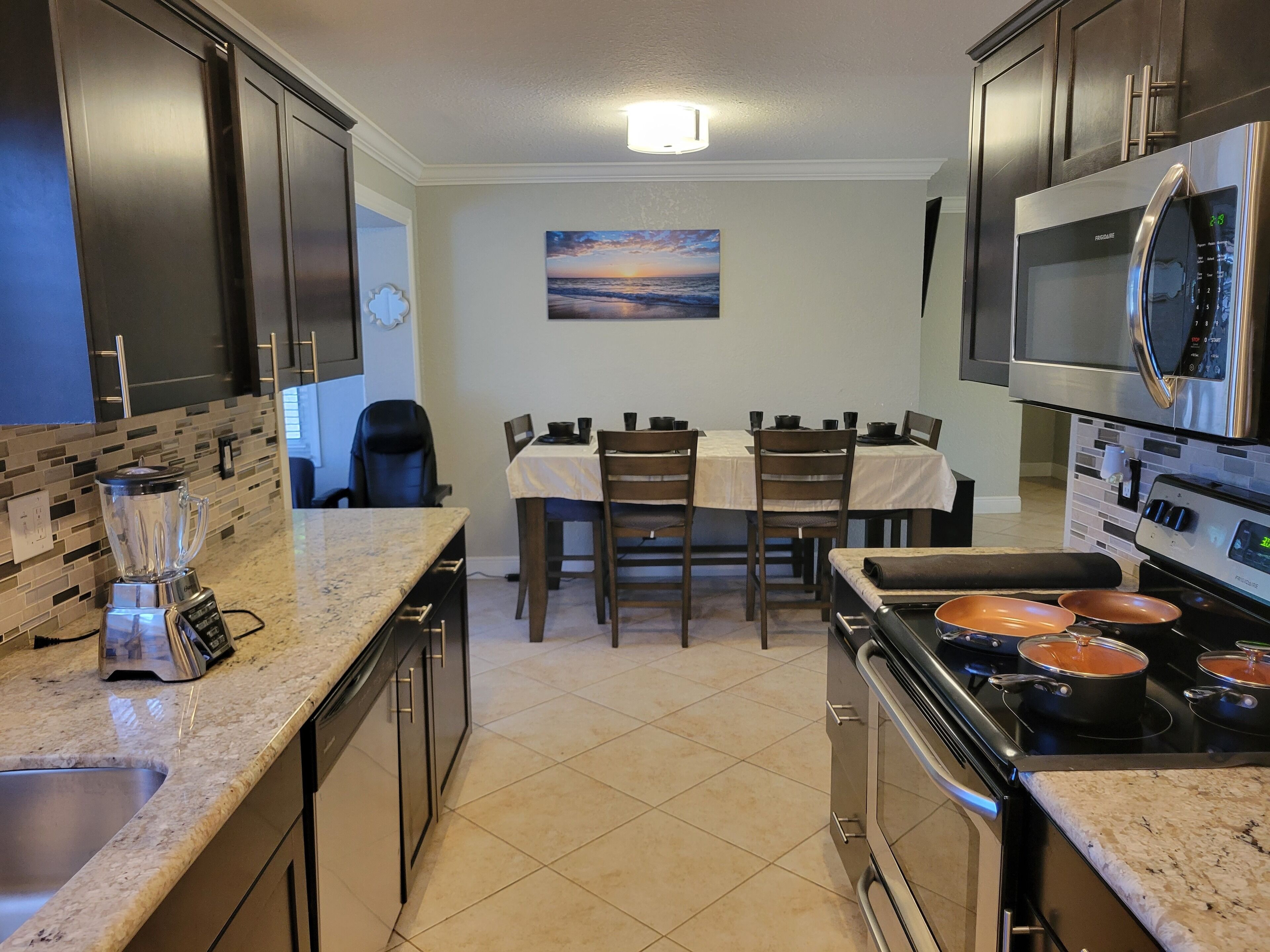 A modern kitchen with granite countertops, stainless steel appliances, and a dining area with a table and chairs.