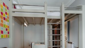 Ein Zimmer mit Etagenbett, Schreibtisch, Stuhl und Heizkörper.