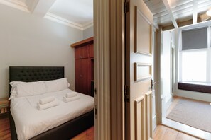 A bedroom with a bed, a wardrobe, and a door leading to a balcony. - Historic two bed Apartment in the City Centre (Bristol)