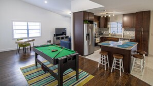 A modern kitchen with dark wood cabinets, a stainless steel refrigerator, and a bar area with stools.