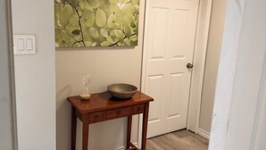 A hallway with a wooden table, a bowl, and a wall-mounted artwork. - Short term rental (Sydney)