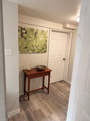A hallway with a wooden table, a bowl, and a wall-mounted artwork.