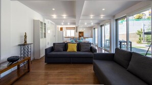 A modern living room with a sofa, a coffee table, and a dining area with a table and chairs. - Pool Villa & Beach House (Torre de Benagalbón)