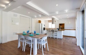 Una cocina moderna con armarios blancos, una mesa de comedor de madera y cristalería azul.