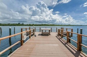A wooden pier extending into calm water, with a bench and railing in the center. - Beautiful Barefoot Beach Resort Condo B207 on Boca Ciega Bay with beach access  (Indian Shores)