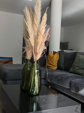A modern living room with a glass coffee table, a grey sofa, and a vase with pampas grass. - Stunning Villa with a Hot Tub (Grabels)
