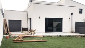Une maison moderne à l’extérieur blanc, dotée d’un garage et d’une pelouse bien entretenue.
