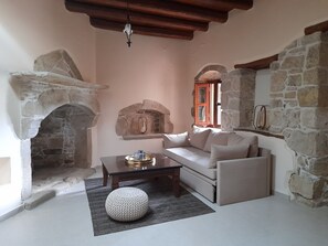 Una habitació acollidora amb una llar de pedra, un sofà, una taula de centre i un llum penjant.