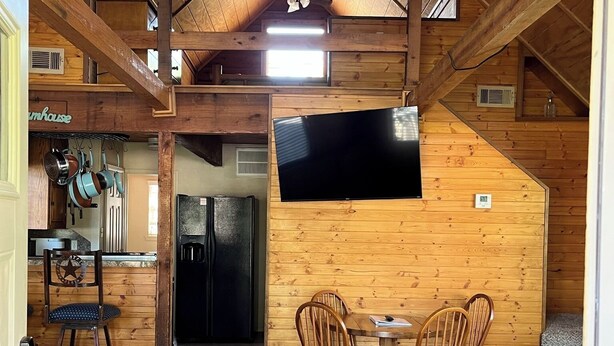 A cozy cabin interior with a dining area, kitchen, and a ceiling fan. - The Cedar Shack near Lake Conroe (Montgomery)