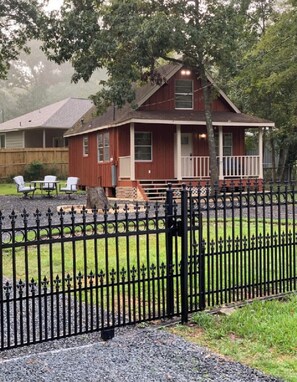 Situated in a serene grassy area, this charming building features a cozy front porch and a gabled roof.