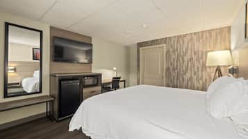 Una camera d'albergo con un letto, una scrivania, una televisione, uno specchio e una porta.