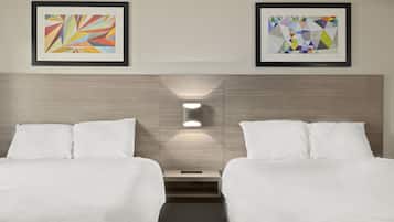 A hotel room with two beds, a nightstand, and two framed abstract artworks on the wall.