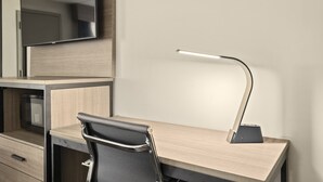 A modern hotel room with a desk, chair, and a flat-screen TV mounted on the wall.