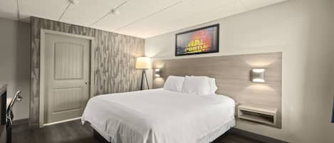 A hotel room with a large bed, a headboard with integrated lighting, a wall-mounted TV, and a bedside table.