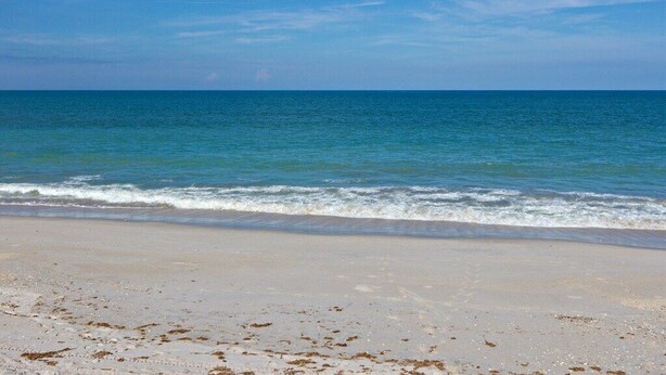 A beach with clear blue water and a sandy shore.