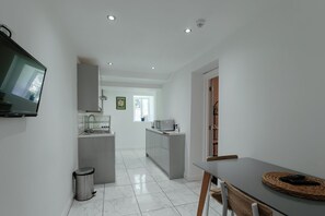 A modern kitchen with a TV, microwave, and sink. - Contemporary Garden Flat in Clifton (Bristol)
