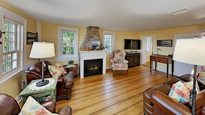 A living room with a fireplace, leather sofas, wooden flooring, and a television.
