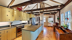 A spacious kitchen with wooden beams, a central island, and light-colored cabinets.