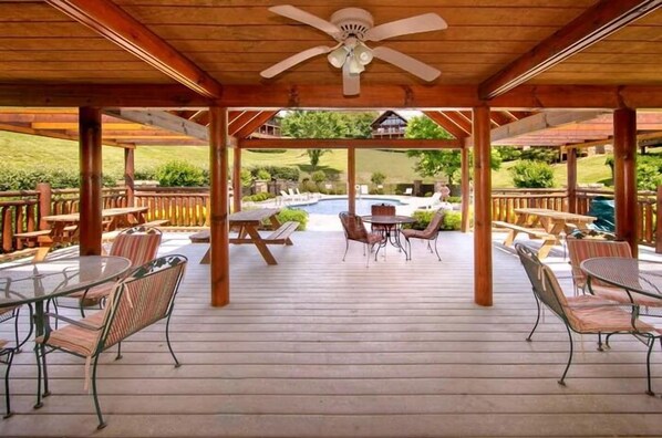 Un'area esterna coperta con piscina, terrazza in legno e zone relax.