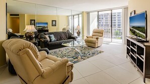 A modern living room with a sofa, armchairs, a coffee table, and a TV. - This 2/2 condo is just steps away from the beach (Marco Island)