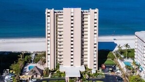 Un hôtel de grande hauteur, avec de nombreux étages, une piscine et une vue sur la plage.