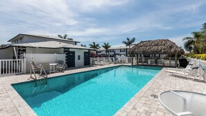 A rectangular swimming pool with clear blue water, surrounded by a white fence and lounge chairs. - Lovely 2 bedroom 2.5 bath condo (Marco Island)