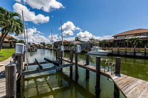 A marina with docked boats, wooden walkways, and houses in the background.