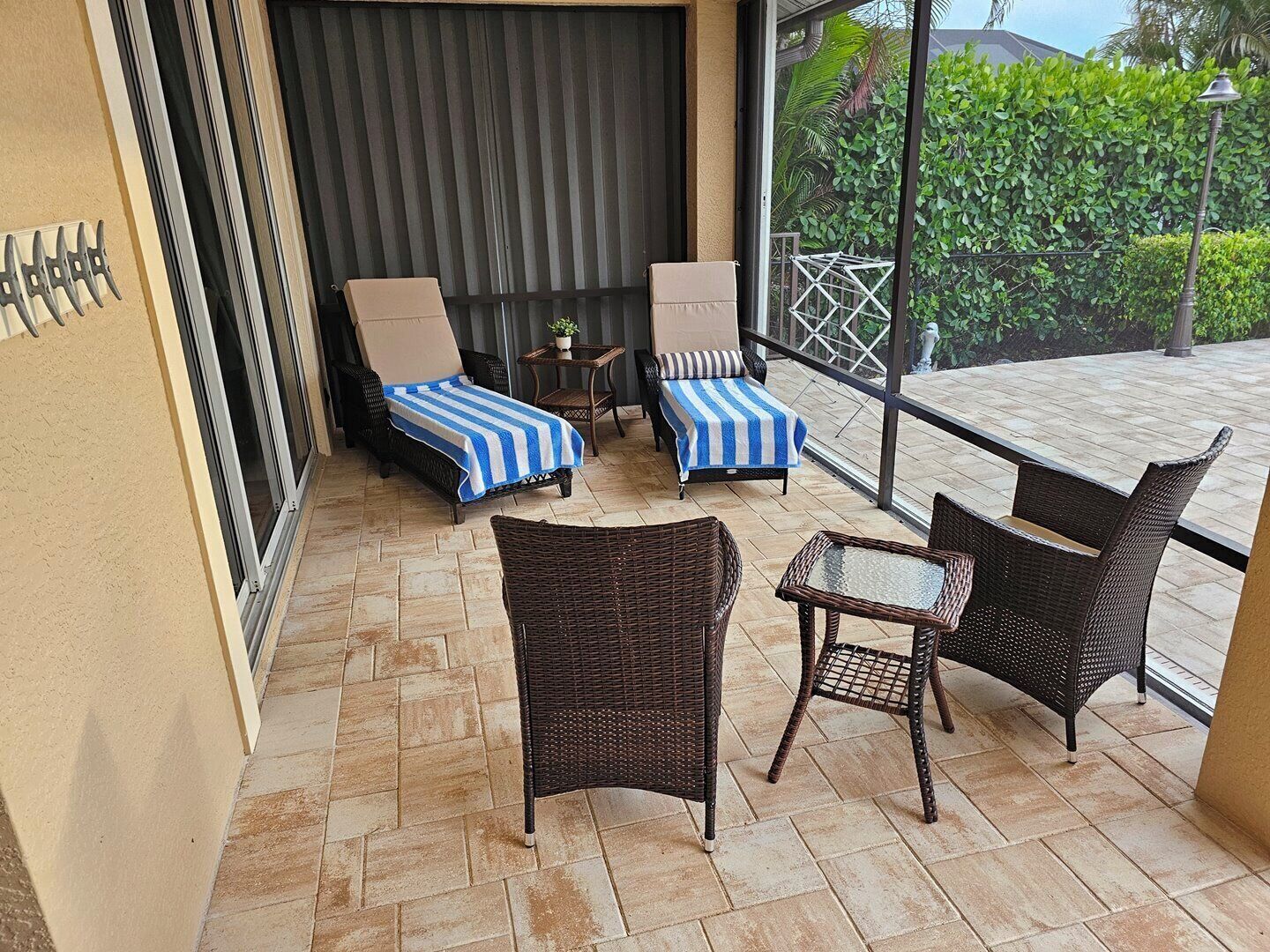 A balcony with wicker furniture, two lounge chairs, and a small table.