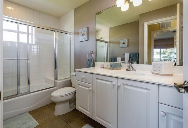 Une salle de bain avec une douche à parois de verre, des toilettes blanches et un meuble-lavabo avec un miroir.
