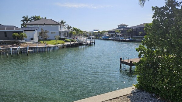 A marina with docked boats, a white building with a balcony, and a clear blue sky. - Newly renovated in March 2025! 3/2 waterfront pool home! (Marco Island)