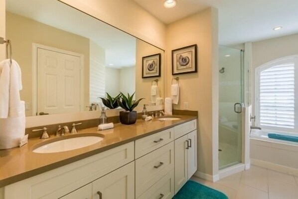 A modern bathroom with a large mirror, two sinks, a shower, and a bathtub. - Gorgeously renovated 4 Bdr, 3 Bth, waterfront home (Marco Island)