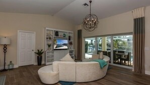 Uma sala de estar moderna com um sofá seccional, uma televisão e um candelabro.