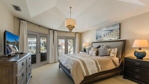 A bedroom with a large bed, a television, a dresser, a nightstand, and a chandelier. - Perfect 4/2  home for your Marco Island vacations (Marco Island)