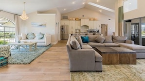 A spacious living area with a large sectional sofa, a coffee table, and a dining area with a kitchen in the background. - Perfect 4/2  home for your Marco Island vacations (Marco Island)