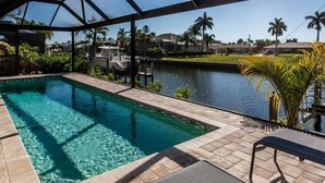 A swimming pool with a clear view of a river and palm trees in the background. - A perfect home to fully enjoy all of Marco Island (Marco Island)