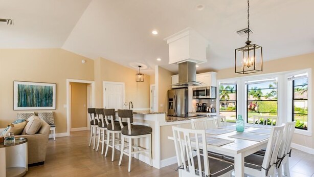A spacious kitchen with a dining area, a large island, and a view of a garden through the windows. - A perfect home to fully enjoy all of Marco Island (Marco Island)