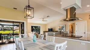 A modern kitchen with a dining area, large windows, and a view of a pool. - A perfect home to fully enjoy all of Marco Island (Marco Island)