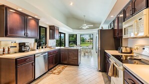 A modern kitchen with dark wood cabinets, stainless steel appliances, and a large island. - 4 bedroom, 3 bath home with heated pool (Marco Island)