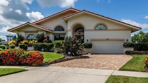 A two-story house with a garage, a driveway, and well-maintained landscaping. - 4 bedroom, 3 bath home with heated pool (Marco Island)