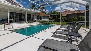 Un espace piscine doté d’une enceinte en verre, de chaises longues et offrant une vue dégagée sur le quartier environnant.
