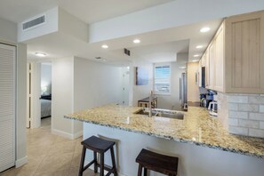 Una cocina moderna con encimeras de granito, un lavamanos de acero inoxidable y armarios de madera.