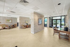 A spacious lobby with a high ceiling, patterned walls, and a mix of seating arrangements including sofas and chairs.