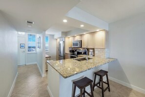 A modern kitchen with granite countertops, stainless steel appliances, and wooden cabinets. - Beautifully updated  2/2 condo with Gulf views (Marco Island)