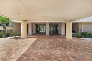 A covered entrance with a brick floor, columns, and a glass door leading inside. - Beautifully updated  2/2 condo with Gulf views (Marco Island)