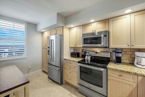 A modern kitchen with stainless steel appliances, wooden cabinets, and a granite countertop.