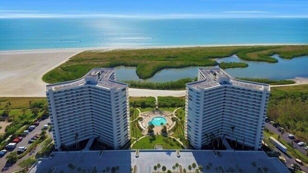 Un hôtel de grande hauteur doté d’une piscine centrale et offrant une vue sur la plage et la mer.