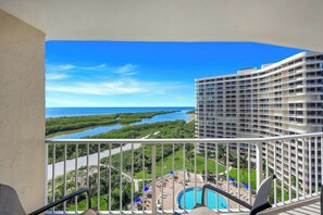 A high-rise hotel with a pool and a view of a coastal landscape.