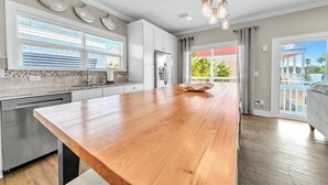 A modern kitchen with a wooden island, stainless steel appliances, and a view to the outside.